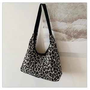 Close-up of leopard print canvas tote bag with black wide leather shoulder strap detail