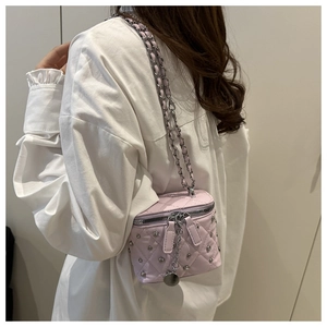 Detail of pink quilted mini box bag with silver studs and woven leather chain strap
