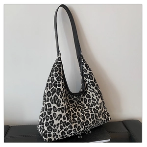 Detail of leopard print hobo tote bag featuring black leather straps and soft structure