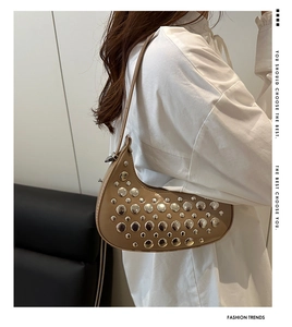 Detailed close-up of a crescent-shaped bag with silver rivets and polished finish