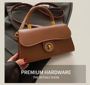Nahaufnahme einer karamellbraunen Ledertasche mit rundem goldfarbenem Drehverschluss