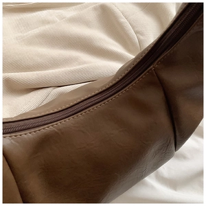 Detail of dark brown faux leather texture and smooth zipper on slouchy dumpling bag