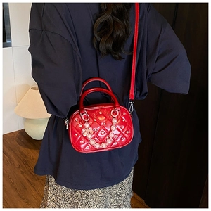 Detail view of red quilted boston bag with rhinestone accents and pearl chain handle