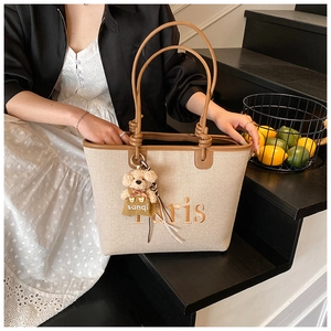 Detail of beige canvas tote with Paris embroidery and cute teddy bear charm