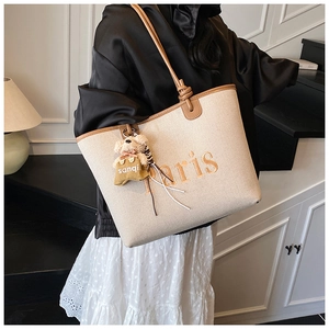 Detail of beige canvas tote bag with brown faux leather trim and Paris embroidery