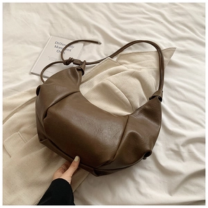 Detailed view of the brown ruched faux leather texture on the crescent shoulder bag
