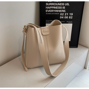 Détail d'un sac seau en cuir blanc crème avec boucle dorée et logo de marque embossé