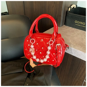 Detail of red quilted patent leather bowling bag with silver studs and pink bead chain