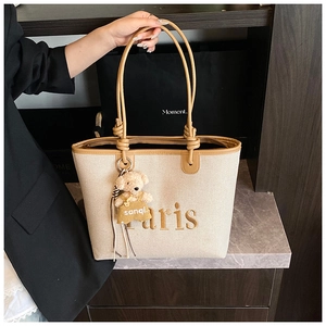 Detail of canvas tote bag with Paris embroidery, leather trim and bear charm accessory
