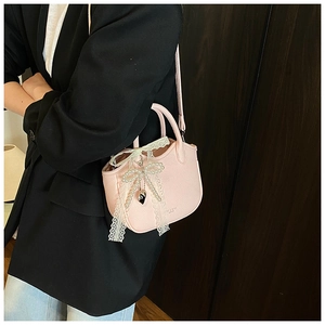 Detail of pink faux leather handbag with lace bow, pearl beads and heart pendant