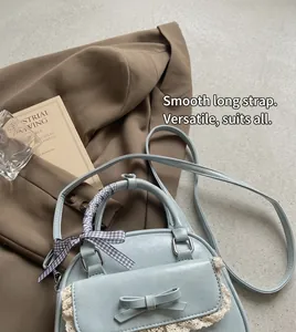 Detail of light blue crossbody bag with white lace trim and plaid scarf handle