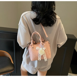 Detail of pink pebbled leather bucket bag with pearl heart charm and lace bow