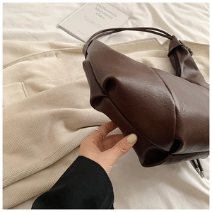 Detail of dark brown soft leather tote showing rich texture and elegant pleated design