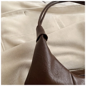 Close-up of coffee brown leather bag showing textured grain and pleated seam details