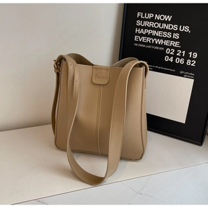 Détail d'un sac seau beige en similicuir avec logo embossé et large bandoulière