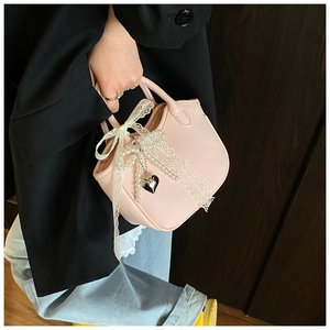 Detailed shot of pink pebble leather handbag with lace bow and pearl heart charm