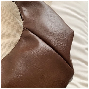 Macro detail of dark brown leather texture with precise stitching and zipper on hobo bag