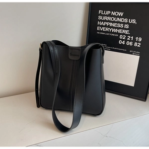 Détail d'un sac seau noir minimaliste avec logo de marque et couture verticale élégante