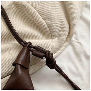 Detailed close-up of the knotted leather shoulder strap on a dark brown hobo bag