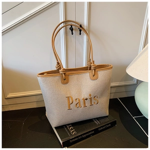 Close-up of canvas tote with brown leather trim and Paris embroidery on art books