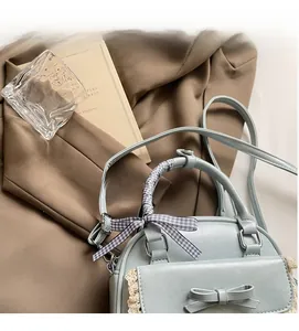 Detail showing mint green crossbody bag with bow, lace edge, and plaid scarf handle