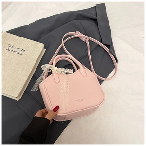 Close-up of pink litchi grain leather handbag with delicate white lace bow and strap