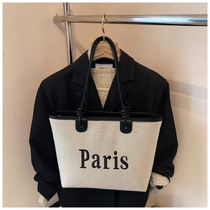 Detail of canvas tote bag with Paris print and black leather handles on a hanger