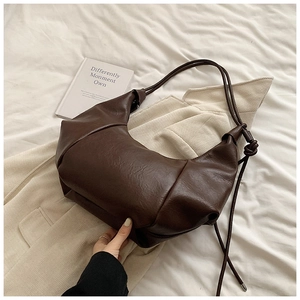Detail of soft dark brown leather hobo bag with texture pleats and knot strap