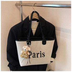 Detail of off-white canvas tote bag with Paris print and cute puppy charm ornament