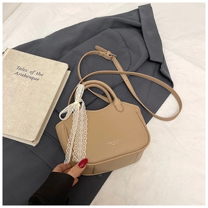Detail of khaki leather handbag with lace bow and adjustable strap on soft fabric