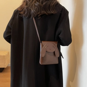 Close-up of a dark brown leather phone bag with cute bunny ears and cross-eye detail