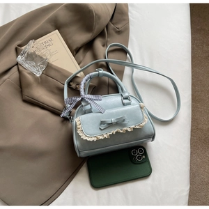 Detail of light blue handbag with leather bow, lace trim and checkered ribbon handle