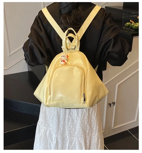Gros plan d'un sac à dos en cuir verni jaune vif avec un charmant pendentif astronaute