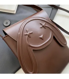 Close-up of brown leather phone bag with cute cartoon rabbit relief and brand logo