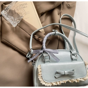 Detail of light blue handbag featuring lace trim, bow, and silk scarf handle decoration