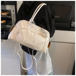 Dettaglio borsa a tracolla color crema con cuciture stile baseball e testo a rilievo