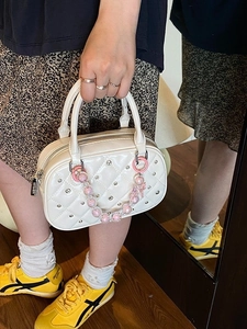 Chic beige quilted Boston bag with rivet studs and beaded chain handle detail