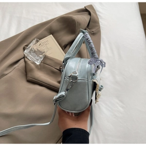 Detail of light blue leather handbag featuring a silk scarf handle and lace side pocket
