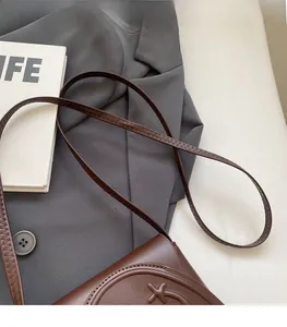 Close-up of the durable stitched brown faux leather strap on a stylish crossbody bag