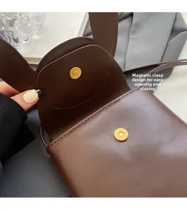 Detail of bunny ear flap and magnetic snap closure on a chocolate brown mini bag