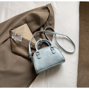 Detail of light blue PU leather handbag with adjustable silver buckle strap on fabric
