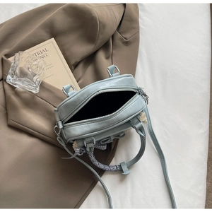Top view of light blue crossbody bag with checkered bow and lace on vintage books