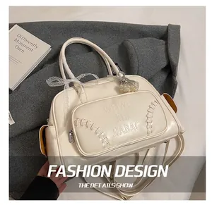 Dettaglio della borsa in pelle lucida bianca con fiocco in pizzo e ciondolo di perle