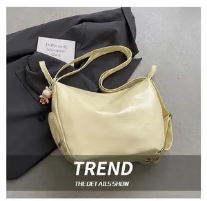 Détail d'un sac hobo jaune en cuir PU avec pendentif ours et poche latérale zippée