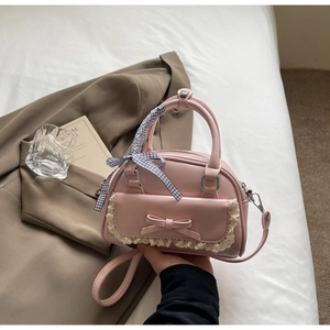 Detail of pink PU handbag featuring lace trim, bow decoration and checkered silk ribbon handle