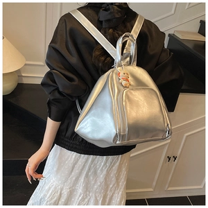 Détail du sac à dos argenté métallisé avec breloque lapin porté par un mannequin en studio
