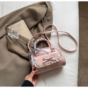 Detailed view of pink leather handbag with lace trim and scarf-wrapped handle