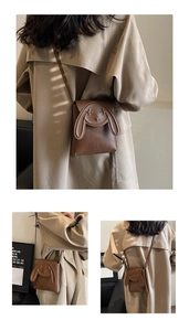 Detail of a brown rabbit-shaped crossbody bag with long strap on a trench coat