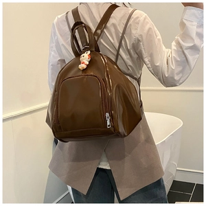 Sac à dos marron foncé en cuir verni avec un charmant lapin en peluche blanc décoratif