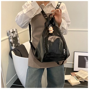 Vue détaillée du sac à dos en cuir verni noir brillant avec fermetures éclair argentées
